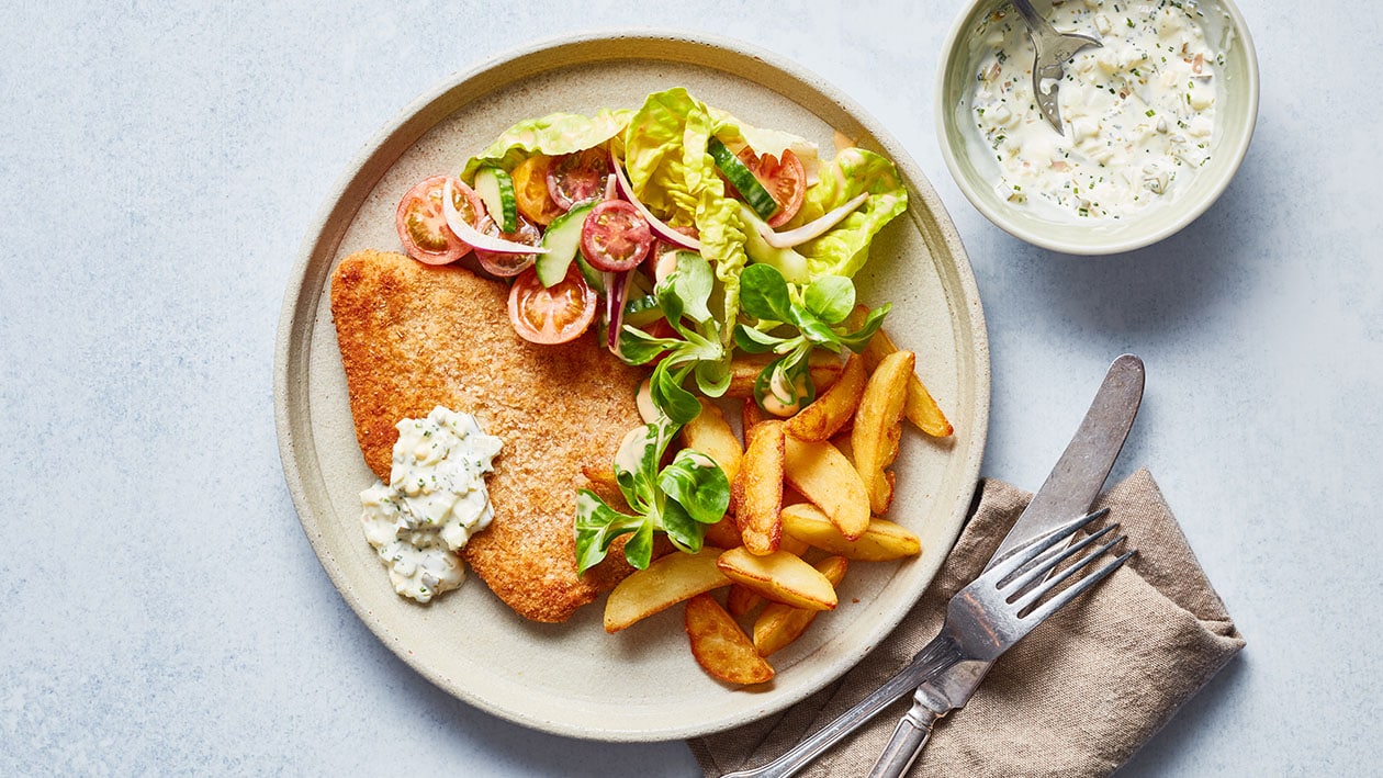 Vegetarische schnitzel met tomatensalade, aardappel wedges en tartaarsaus Vegetarische schnitzel met tomatensalade, aardappel wedges en tartaarsaus